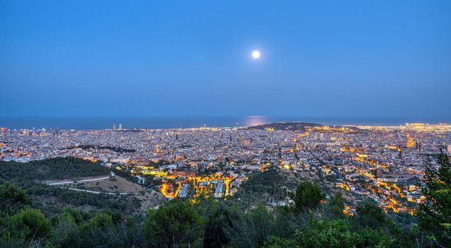 Panorama of Barcelona at night with a full moon
