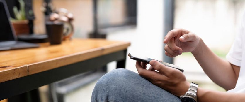 male hands using smartphone at cafe, searching or social networks concept, hipster man typing an sms message to his friend