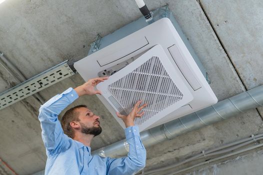 Caucasian bearded man repairing the air conditioner in the office