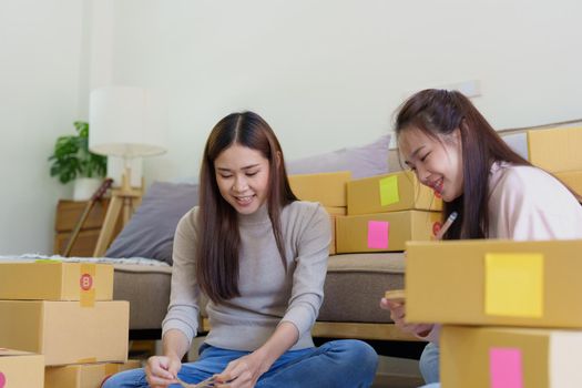 Portrait of Starting small businesses, two Asian woman check online orders Selling products working with boxs freelance work at home office, sme business concepts