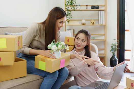 Portrait of Starting small businesses, two Asian woman check online orders Selling products working with boxs freelance work at home office, sme business concepts