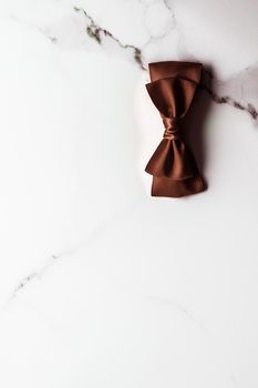 Holiday gift, decoration and sale promotion concept - Chocolate brown silk ribbon on marble background, flatlay