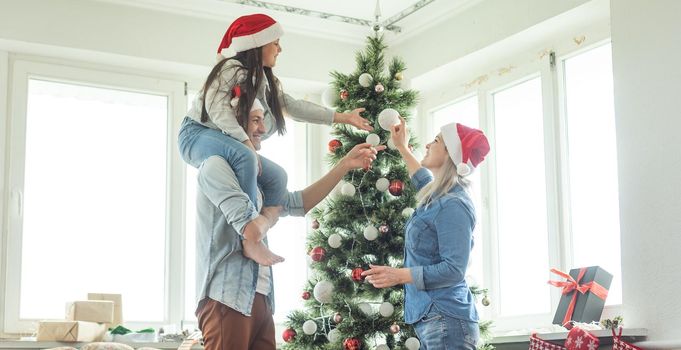 Christmas Family. Happiness. Portrait of dad, mom and daughter at home near the Christmas tree, all are smiling.