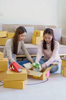 Portrait of Starting small businesses, two Asian woman check online orders Selling products working with boxs freelance work at home office, sme business concepts