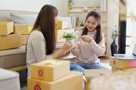 Portrait of Starting small businesses, two Asian woman check online orders Selling products working with boxs freelance work at home office, sme business concepts