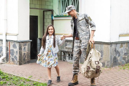 Little child is very happy her father came back from army. Little kid is hugging her father.