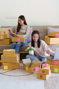 Portrait of Starting small businesses, two Asian woman check online orders Selling products working with boxs freelance work at home office, sme business concepts