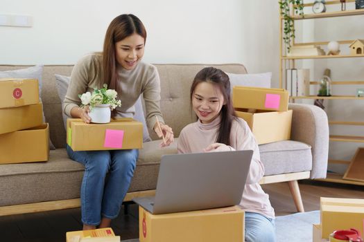 Portrait of Starting small businesses, two Asian woman check online orders Selling products working with boxs freelance work at home office, sme business concepts