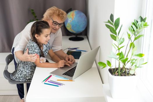 Grandmother and granddaughter using tablet and laptop