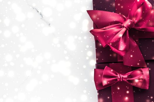 New Years Eve celebration, wrapped luxury boxes and cold season concept - Winter holiday gifts with cherry silk bow and glowing snow on frozen marble background, Christmas presents surprise