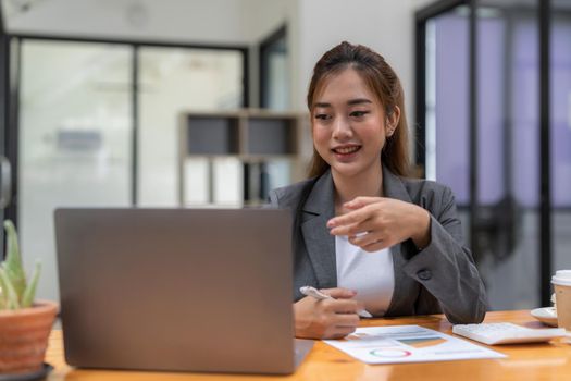 Portrait of smiling asian female self employed freelancer at work using laptop research project. Positive motivated young black lady remote student look at camera distracted from learning.