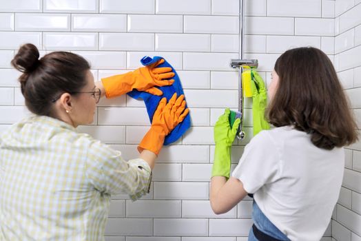 Family mother and teenage daughter cleaning together at home in the bathroom. Child helping parent, housekeeping, lifestyle, housework