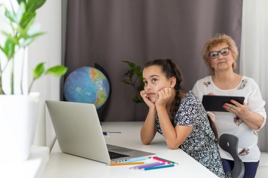 Grandmother and granddaughter using tablet and laptop