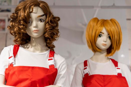 two beautiful mannequin girl in a seller's apron with black and red hair in a clothing store. shopping, fashion, style. Standing woman dummies show collection of clothes