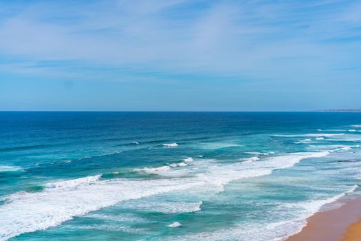 Aerial view of tropical sandy beach and ocean with turquoise water with waves. Sunny day on Atlantic ocean beach in Portugal