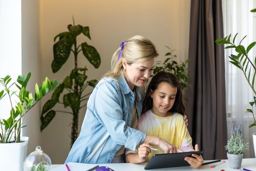 Back to school. Happy child and adult are sitting at desk. Girl doing homework or online education.