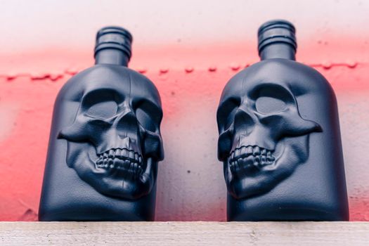 skull-shaped gin bottles. glass bottle in the shape of a human skull. Drink for night party on grey metal background