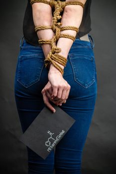 Vertical shot of bound girl holds paper with methamphetamine molecule. Drug addiction and dependence concept.