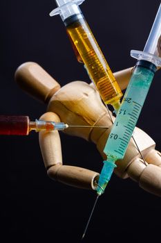 Close-up wooden doll dummy mannequin with stucked syringes. Drug trap concept.