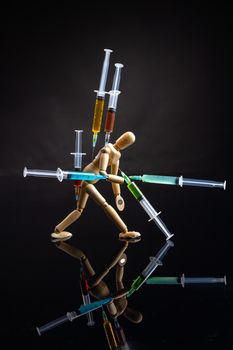 Art object drug dependence and overdose concept. Vertical shot of wooden mannequin on black background.