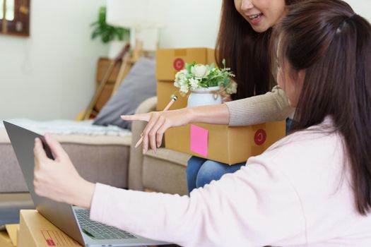 Starting small businesses, two Asian woman check online orders Selling products working with boxs freelance work at home office, sme business concepts