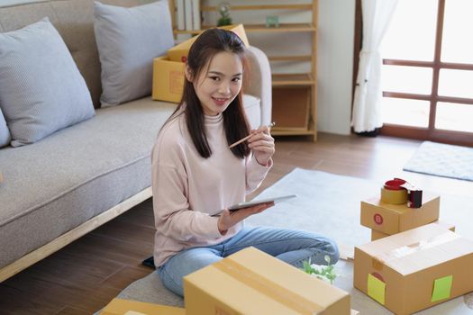 Portrait of Starting small businesses, Asian woman check online orders Selling products working with boxs freelance work at home office, sme business concepts