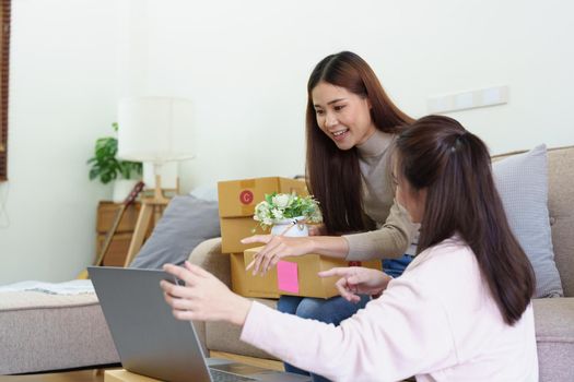 Portrait of Starting small businesses, two Asian woman check online orders Selling products working with boxs freelance work at home office, sme business concepts