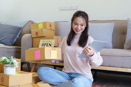 Portrait of Starting small businesses, Asian woman check online orders Selling products working with boxs freelance work at home office, sme business concepts