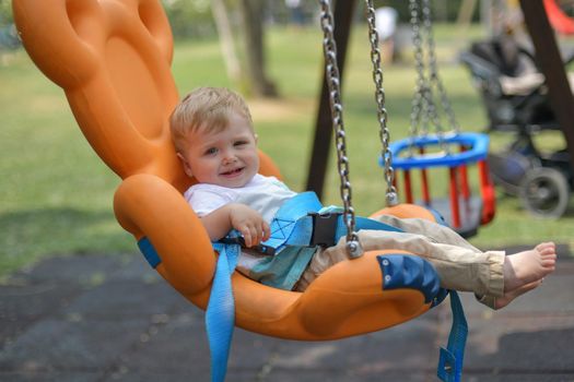 Smiling baby boy sitting in a swing