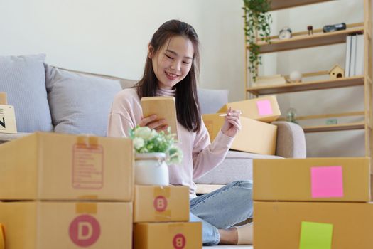 Portrait of Starting small businesses, Asian woman check online orders Selling products working with boxs freelance work at home office, sme business concepts