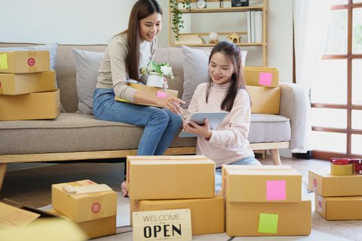 Portrait of Starting small businesses, two Asian woman check online orders Selling products working with boxs freelance work at home office, sme business concepts