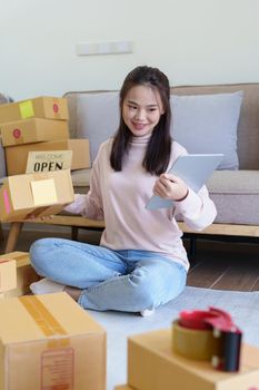 Portrait of Starting small businesses, Asian woman check online orders Selling products working with boxs freelance work at home office, sme business concepts