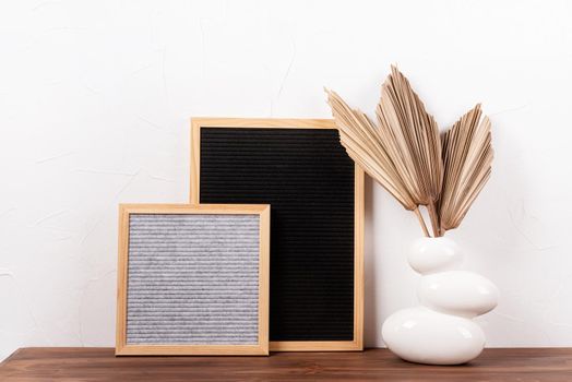 felt letter boards with dry palm leaves on wooden table in a vase , mockup design
