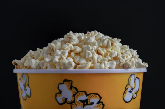close-up of a popcorn container with colored letters on a black background