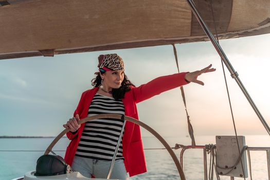 Attractive middle-aged woman at the helm of a yacht on a summer day. Luxury summer adventure, outdoor activities