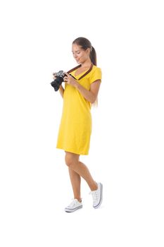 Beautiful woman photographer in yellow dress with photo camera. Full length portrait. Isolated on the white background.