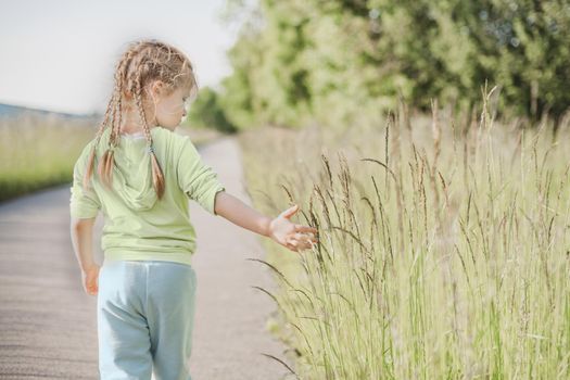 Girl with pigtails touching green grass