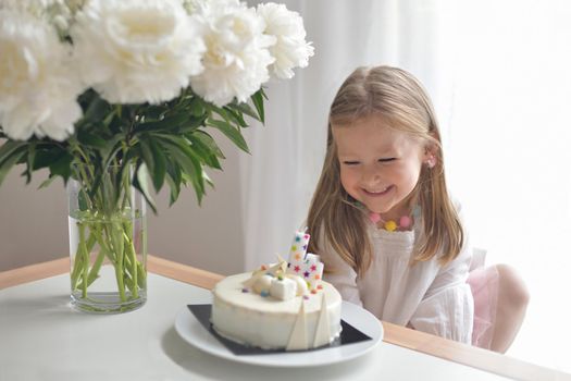 A girl of four years old making wish blowing candles on a cake