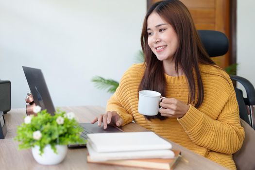 Portrait of an Asian businesswoman or business owner taking a coffee break while working in the office.