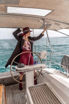 Attractive middle-aged woman at the helm of a yacht on a summer day. Luxury summer adventure, outdoor activities