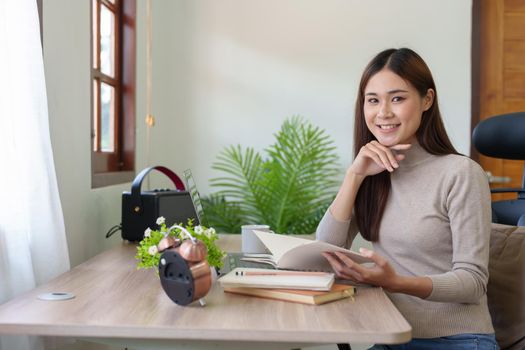 woman sitting at home reading a notebook and using a computer.