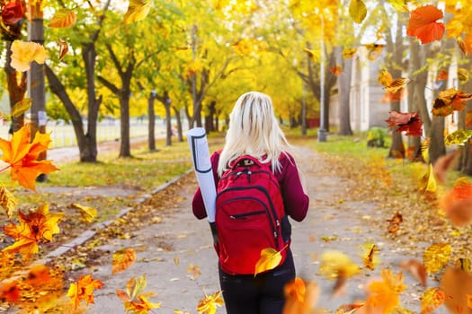 Beautiful girl walking outdoors in autumn. Smiling girl collects yellow leaves in autumn. Young woman enjoying autumn weather. High quality photo