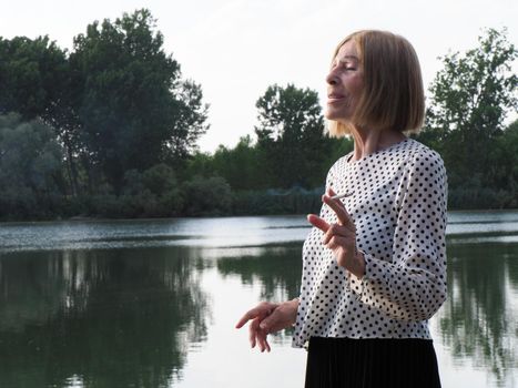 female pensioner having fun and smoking a cigarette in a park - aging free and wellness concept