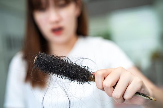 Asian woman have problem with long hair loss attach to comb brush.