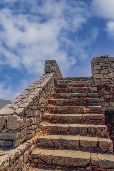 Day view of empty stone old staircase steps without people, against blue sky with clouds.