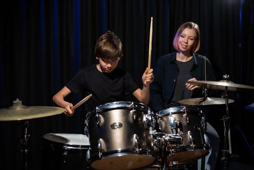 Young woman teaching boy to play drums