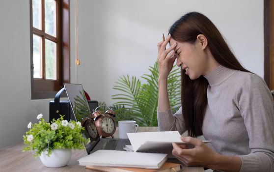 Asian young woman seriously working on computer laptop in house. She thinking find solution problem of work.