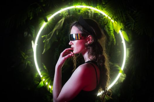 Caucasian woman in panoramic sunglasses against the background of an annular neon lamp in plants
