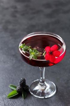 Refreshing lemonade with blackberries, ice and mint on a black background. Copy space,vertical photo
