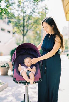Mom stroking a baby in a stroller on the street. High quality photo